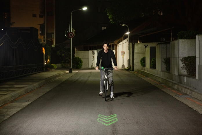 自転車の進路を示す矢印形状に照射されたグリーンレーザー